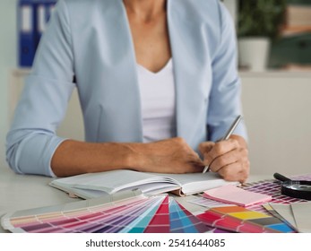 A designer reviewing color samples while taking notes in a creative workspace during the day - Powered by Shutterstock