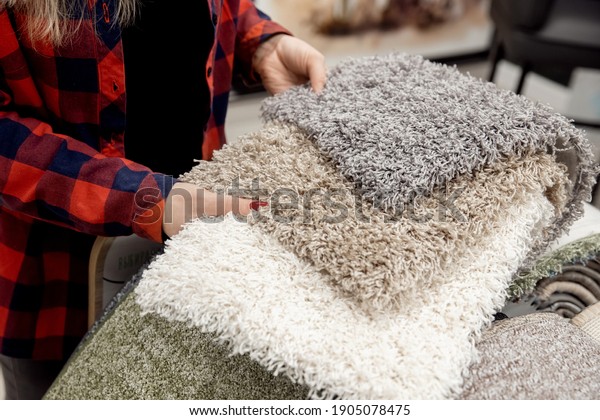 Designer\
shows examples of carpet rugs in textile\
store.