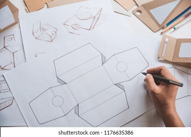 Designer Sketching Drawing Design Brown Craft Cardboard Paper Product Eco Packaging Mockup Box Development Template Package Branding Label . Designer Studio Concept .