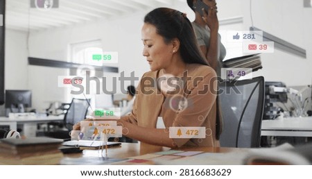 Designer sorting colors, tapping tablet, making social alerts overlaying then fading for marketing. Focus, openplan, office, swatches, cords, touchscreen, daylight