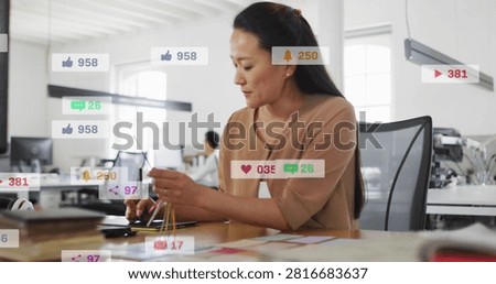 Designer sorting colors, tapping tablet, making social alerts overlaying then fading for marketing. Focus, openplan, office, swatches, cords, touchscreen, daylight