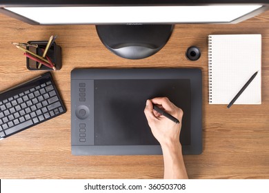 Designer using graphic tablet in the office. Top view workplace with tablet, keyboard and computer. 