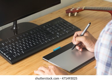 designer using graphic tablet, ukulele on desk