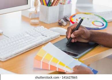 Designer using graphics tablet while holding colour charts - Powered by Shutterstock