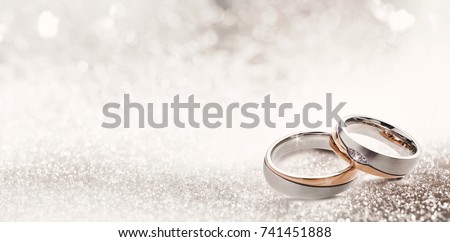 Designer wedding rings in the corner on a sparkling glitter background in panoramic banner format with copy space and selective focus
