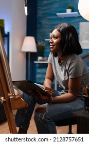 Designer Woman Student Browsing Draw Inspiration On Tablet Computer Sitting In Front In Canvas Drawing Sketch Using Graphic Pencil In Art Atelier. Young Artist Working At Art Autenthic Masterpiece