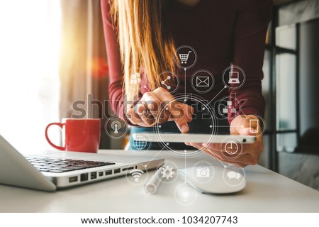 designer woman using smart phone for mobile payments online shopping,omni channel,sitting on table,virtual icons graphics interface screen in morning light
