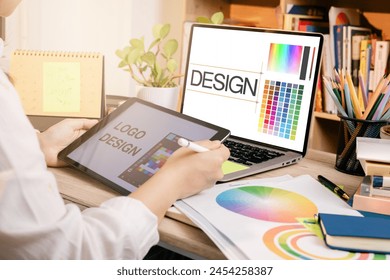 Designer at work on a table, selecting color shades for creative graphic design with laptop and tablet - Powered by Shutterstock