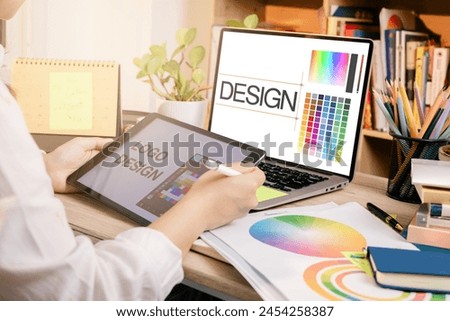Designer at work on a table, selecting color shades for creative graphic design with laptop and tablet