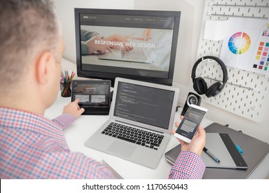 Designer working on responsive web design project. Web developer and programmer working in office with modern devices on desk