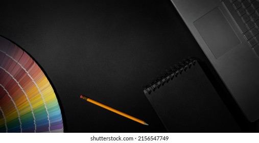 designer workspace with color swatch, laptop and notepad on black background. banner with copy space - Powered by Shutterstock