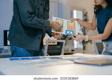 Designers collaborating on mobile app ui, analyzing prototypes in office. Deeply engaged in strategizing for seamless user experience - Powered by Shutterstock