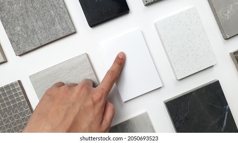 designer's hand choosing samples of interior stone material consists concrete tiles, quartz stones, artificial stones, graphic tile. top view of interior selected material for mood and tone board.  - Shutterstock ID 2050693523