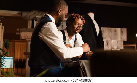 Designers reviewing material for items in atelier, choosing professional fabric on workstation before creating clothing line. Team of tailors manufacturing clothes with tools. Handheld shot. - Powered by Shutterstock