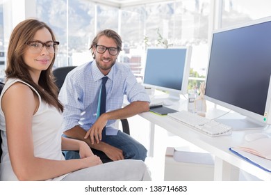 Designers sitting at their desk and smiling in bright modern office