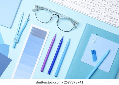 Designer's workplace. Flat lay composition with stationery and keyboard on light blue background