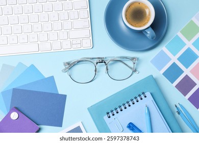 Designer's workplace. Flat lay composition with stationery and keyboard on light blue background