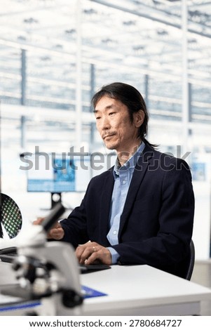 Designing microchip layout, semiconductor manufacturing and senior hardware developer using PC in research facility. Optimizing PCB network topology, computer and elderly Asian man at office desk