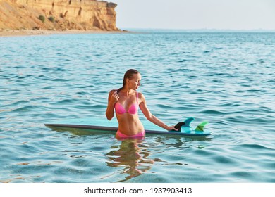 Desire of adventure, summer time and time to relax idea. Lady on vacation with surfboard posing on mountain background.