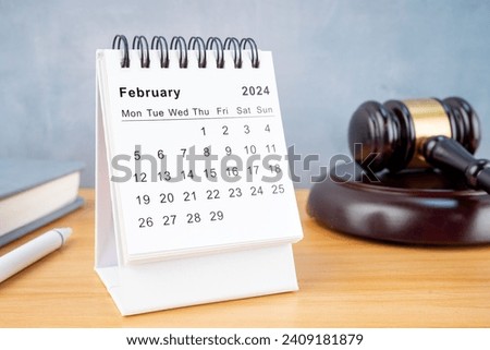 Desk calendar for February 2024 and judge's gavel on the worktable.
