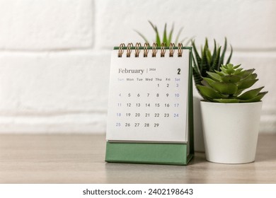 Desk calendar for February 2024 and on the table with copy space