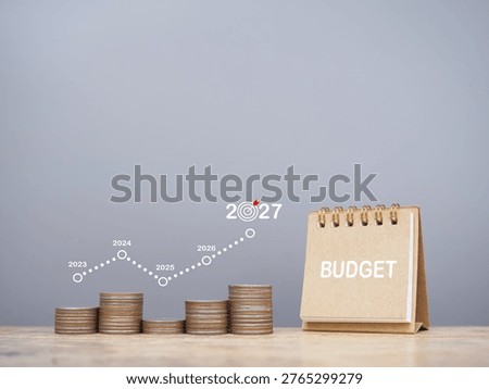 Desk calendar and stack of coins with graph. The concept about budget planning and allocation in year 2027
