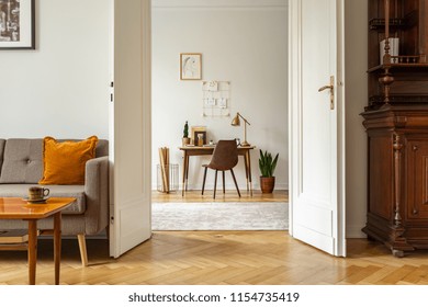 Desk And Chair In A Home Office Interior. View Through Door Of A Vintage Living Room. Real Photo