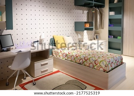 Desk with computer and soft bed located in contemporary teenager bedroom at home
