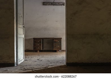 Desk In An Empty Room In An Abandoned Office Building, Looking Through A Doorway.