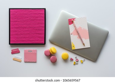 Desk Flat Lay With Blank Pink Letter Board, Laptop Computer, Notebook, Bright Office Accessories And French Macarons