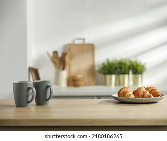 Desk of free space and fresh croissants with gray mugs. Kitchen interior and shadow on wall.  - Shutterstock ID 2180186265