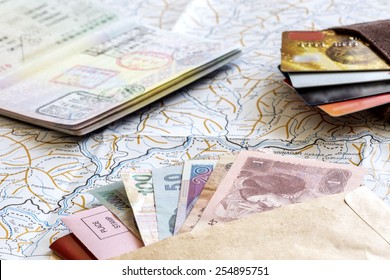 Desk of frequent traveler - angle view.
The composition of essential items for trip: passport with entry stamps, cash notes of different countries, wallet with credit cards, and detailed map - Powered by Shutterstock