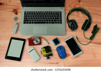 Desk with gadgets or electronic equipment for daily use, laptop computer, cell phones and digital camera on wooden floor background - Shutterstock ID 1376255498