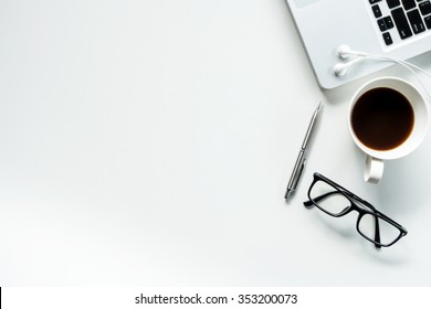 Desk with laptop, eye glasses, earphone, pen and a cup of coffee. Top view with copy space.