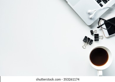 Desk With Laptop, Eye Glasses, Earphone, Pen, Document Clips And A Cup Of Coffee. Top View With Copy Space.