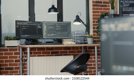 Desk With Multiple Computer Monitors Displaying Parsing Code And Programming Language Compiling In Empty Software Developing Agency Office. Servers Cloud Computing Big Data Algorithms.