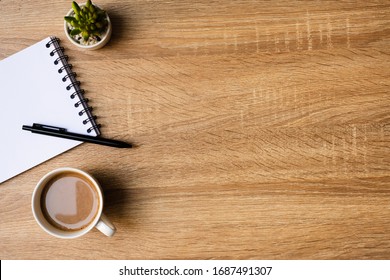 Desk Office With Blank Notepad, Coffee Cup And Pen On Wood Table. Flat Lay Top View Copy Spce.