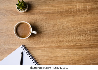 Desk Office With Blank Notepad, Coffee Cup And Pen On Wood Table. Flat Lay Top View Copy Spce.