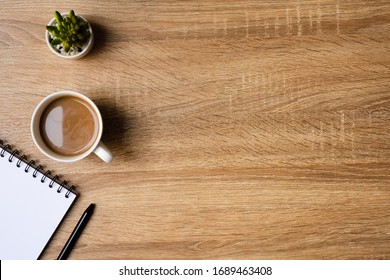 desk office with blank notepad, coffee cup and pen on wood table. Flat lay top view copy spce. - Powered by Shutterstock