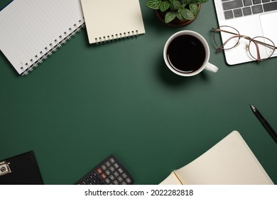 Desk office with laptop, blank notebook, flower, coffee cup, glasses and pen on green table. Flat lay top view copy space. Home office. - Shutterstock ID 2022282818