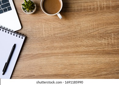 desk office with laptop, blank notepad, coffee cup and pen on wood table. Flat lay top view copy spce. - Shutterstock ID 1691185990