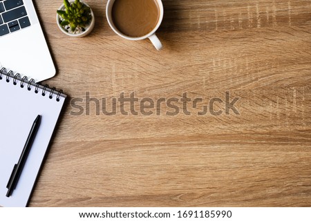 desk office with laptop, blank notepad, coffee cup and pen on wood table. Flat lay top view copy spce.