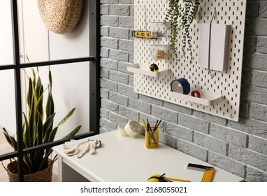 Desk And Pegboard With Tools On Grey Brick Wall