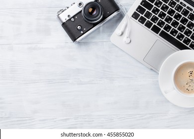 Desk Table With Laptop, Coffee Cup, Headphones And Camera On Wooden Table. Workplace. Top View With Copy Space.