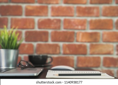 Desk of work table on brick wall background in office with laptop computer , notebook , calculator and a cup of coffee for creative marketing plan to success planning of company