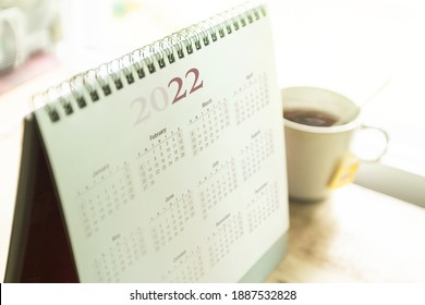 Desktop-Kalender 2022 mit Teebecher auf Holzschreibtisch im Privatbüro