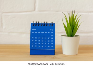 Desktop calendar for July 2023 on the table with a space to copy.