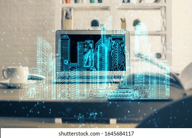 Desktop computer background in office and big town buildings hologram drawing. Double exposure. Smart city concept.