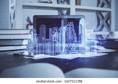 Desktop computer background in office and big town buildings hologram drawing. Double exposure. Smart city concept.