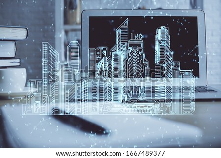 Desktop computer background in office and big town buildings hologram drawing. Double exposure. Smart city concept.